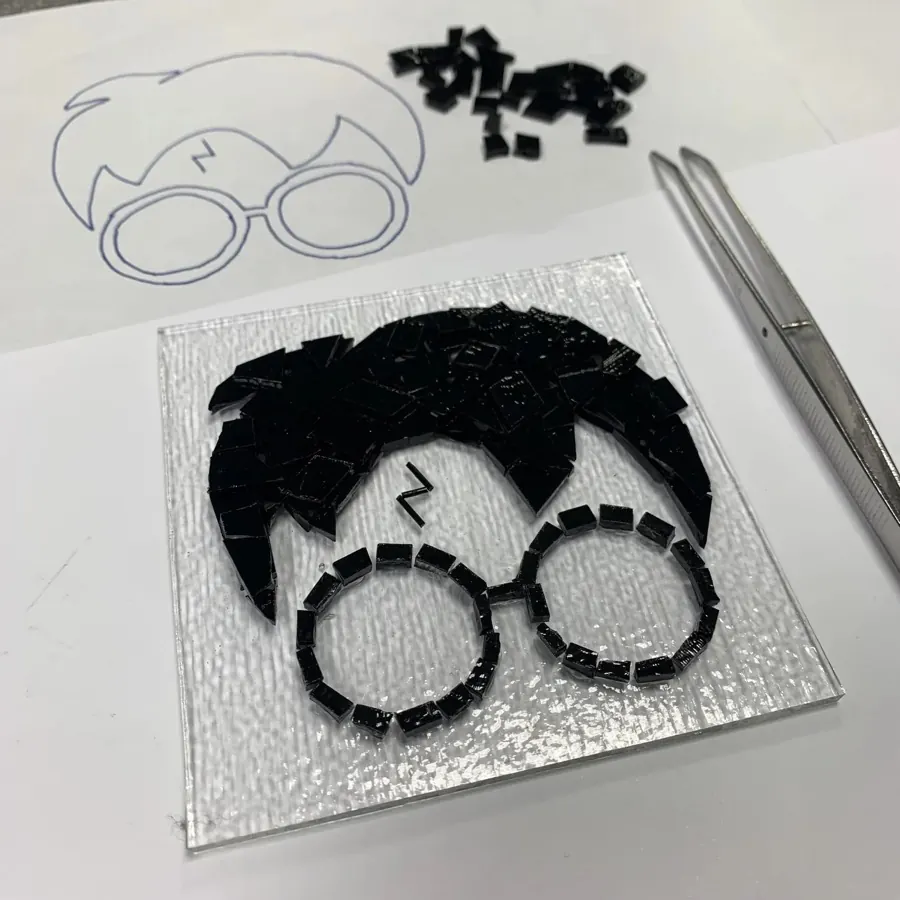 A fused glass tile showing Harry Potter’s glasses and hair
